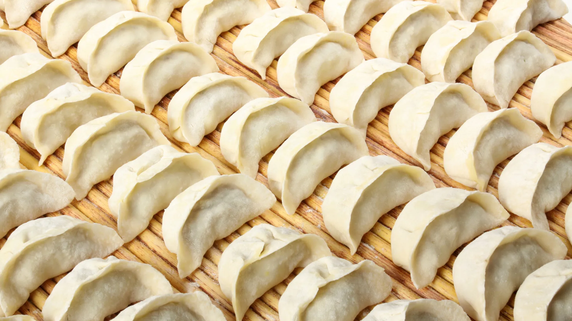 Raw handmade dumplings laid neatly on bamboo mat at Dumpling Legend, a Chinese Restaurant in Lakewood